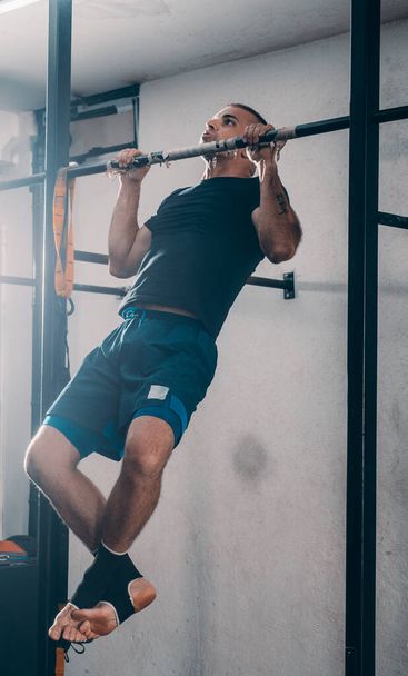 Crossfit man doing pull-ups on chin-up bar during workout outdoors - Foto, Imagem