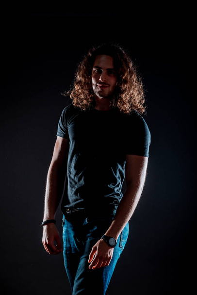 Attractive stylish man posing in black top isolated on black background - Fotoğraf, Görsel