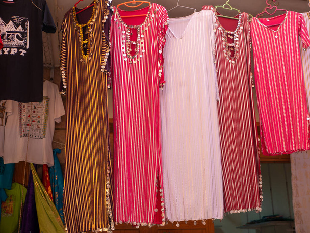Vestidos de colores brillantes decorados en estilo oriental se venden en exhibición en una tienda de ropa. Luxor, Egipto. - Foto, imagen