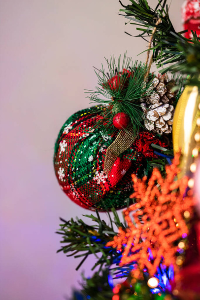 A vertical shot of beautiful decorations and ornaments hanging on a Christmas tree with lights - Fotografie, Obrázek