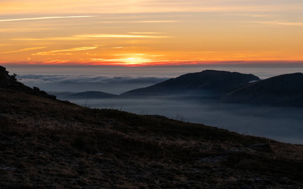 A Breathtaking scene of a sunset from the peaks of mountains and foggy sky - Foto, immagini