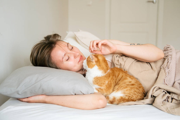 Portrait young beautiful caucasian woman wakes up in the morning. Woman hugging her cat at the morning. Lifestyle with home animals. - Foto, imagen