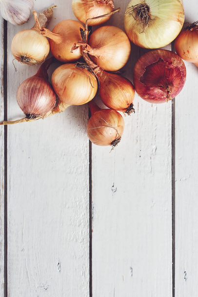 Onions and garlic on a white wooden background, top view. - Photo, Image