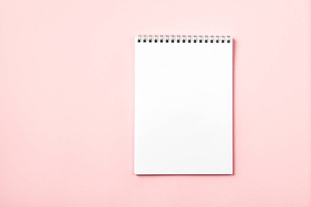 Vista superior de la hoja en blanco del cuaderno sobre un fondo rosa. Copiar espacio. - Foto, imagen