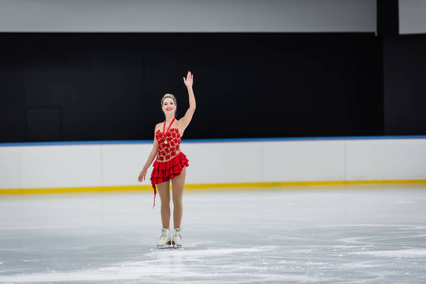 longitud completa de la mujer feliz con medalla saludando mano en la arena de hielo profesional - Foto, imagen
