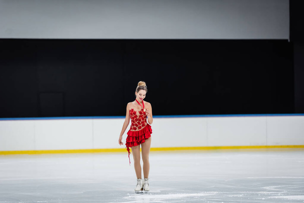 volledige lengte van gelukkig vrouw op zoek naar medaille in professionele ijs arena - Foto, afbeelding