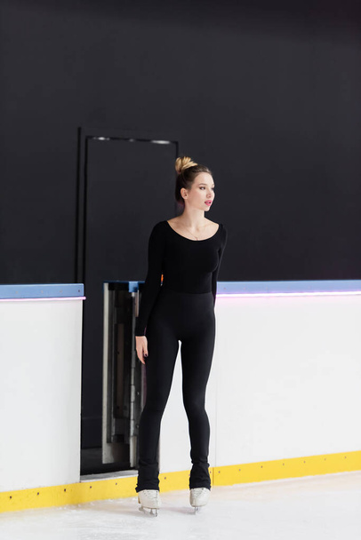 full length of young figure skater in bodysuit standing on frozen ice arena - Photo, Image
