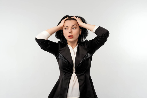 Занепокоєна бізнес-леді в чорній офіційній куртці біла сорочка схоплює голову, стоячи на білому тлі. Концепція бізнесу
 - Фото, зображення