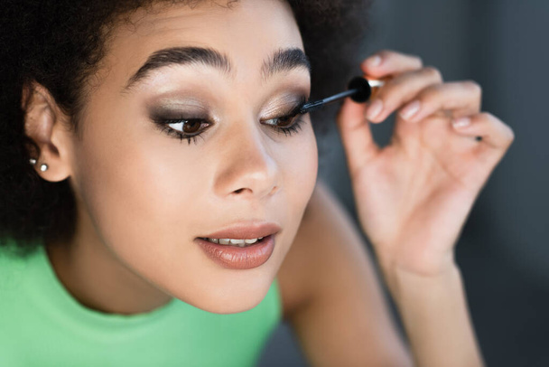 African american woman applying mascara at home  - Foto, afbeelding