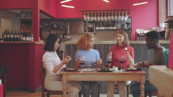 Baráti társaság ül az asztalnál étterem - A fiatalok élvezik az ételt  - Felvétel, videó