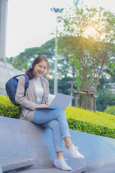 Милая улыбающаяся студентка, держащая планшет и сумку перед торговым центром. - Фото, изображение