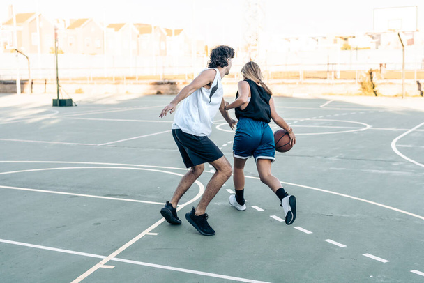Femme rebondissant une balle tout en jouant au basket sur un terrain extérieur - Photo, image