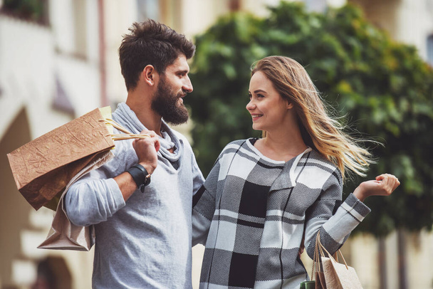 Şehirde yürürken alışveriş torbaları ile genç mutlu çift - Fotoğraf, Görsel