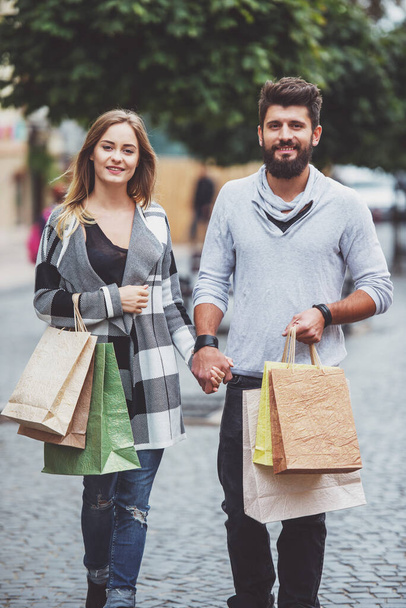 Joven pareja feliz con bolsas de compras mientras camina por la ciudad
 - Foto, Imagen
