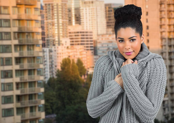 Composite image of portrait of african american woman in sweater against tall buildings. winter season concept - Foto, Imagen