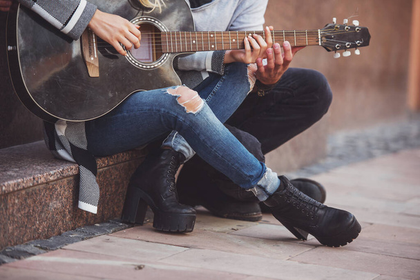 Genç, mutlu bir çift şehirde bir merdiven üzerinde duran gitar çalmak portresi - Fotoğraf, Görsel