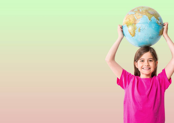 Egy fehér lány portréja, amint egy földgömböt tart a feje fölött zöld és rózsaszín gradiens háttérrel. iskolai és oktatási koncepció - Fotó, kép