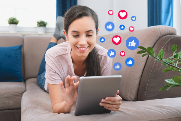 Young woman using social media. Icons flying from the digital tablet - Photo, Image