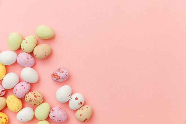 Happy Easter concept. Preparation for holiday. Easter candy chocolate eggs and jellybean sweets isolated on trendy pastel pink background. Simple minimalism flat lay top view copy space. - Photo, Image