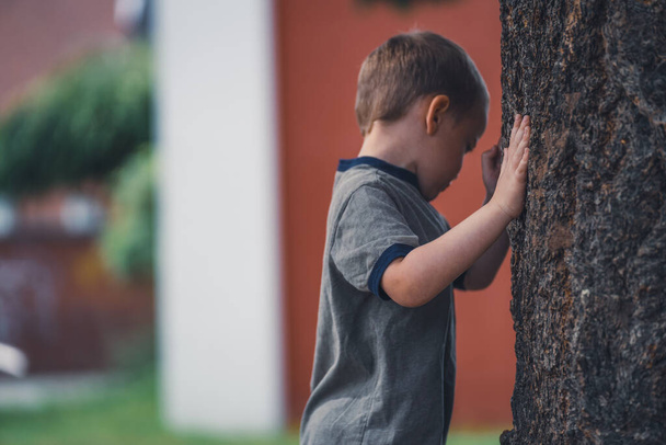 El niño está caminando alrededor de un árbol en el parque. - Foto, Imagen