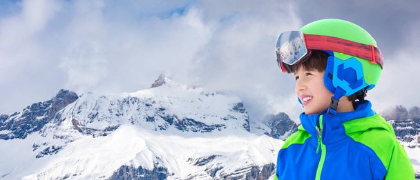Smiling child on the high altitude ski slope in the Italian Alps. Happy child with helmet and ski goggles on the ski slopes. - Photo, Image