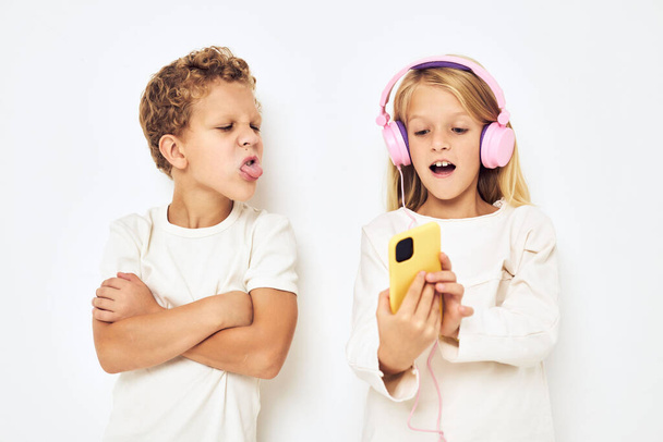 Imagen de niño y niña con auriculares amarillos de color rosa fondo aislado - Foto, Imagen