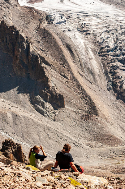 Dos jóvenes trekkers que descienden de la cima del pico Pik Uchitel con cruz. Parque Nacional Alpino Ala Archa Paisaje cerca de Biskek, Cordillera Tian Shan, Kirguistán, Asia Central. - Foto, imagen