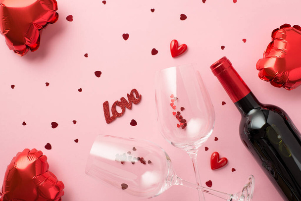 Вид зверху фото прикрас дня святого Валентина повітряні кулі у формі серця напис любов маленькі серця два келихи винограду з конфетті та пляшка вина на ізольованому пастельно-рожевому тлі
 - Фото, зображення