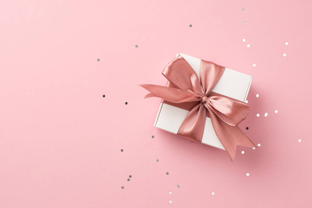 ピンクのサテンリボンの弓と空白のスペースを持つ隔離されたパステルピンクの背景に光沢のあるスパンコールとバレンタインデーの装飾の白いギフトボックスのトップパノラマビュー写真 - 写真・画像
