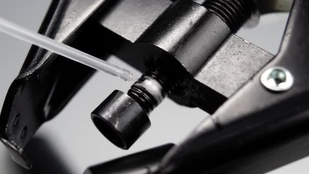 Lubricant spray is sprayed onto a metal mechanical part of black thread press in slow motion. Macro. Industrial technology concept - Felvétel, videó