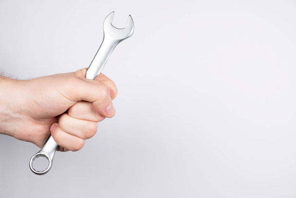 wrench on a white background. Man hand holding a wrench, free space. Repair of machines and equipment - Photo, Image