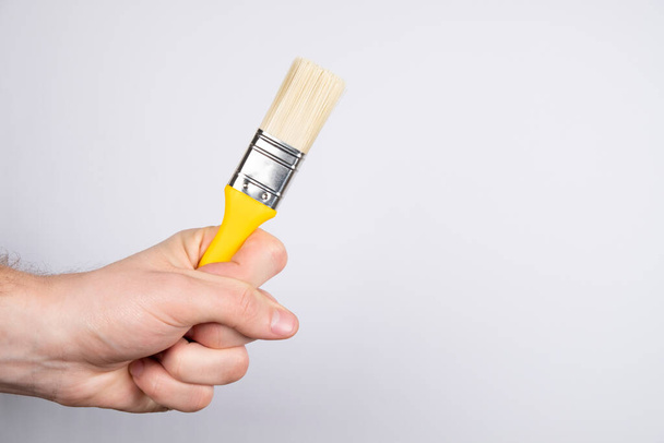 Clean paint brush on a white background. Man hand hold paintbrush - Foto, imagen