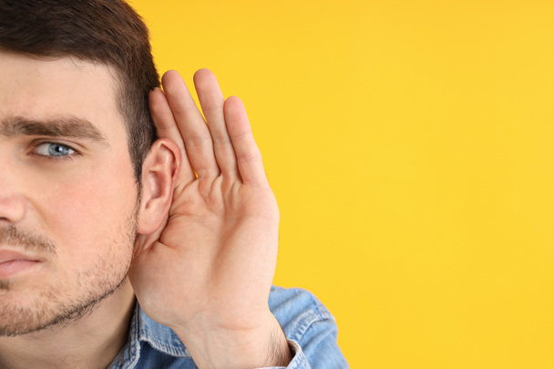 Young man with hearing problems on yellow background - Fotografie, Obrázek