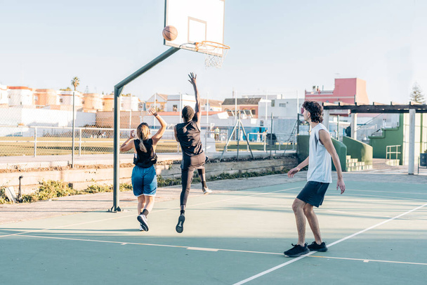 Gente saltando esperando un rebote de una pelota mientras juega baloncesto - Foto, Imagen