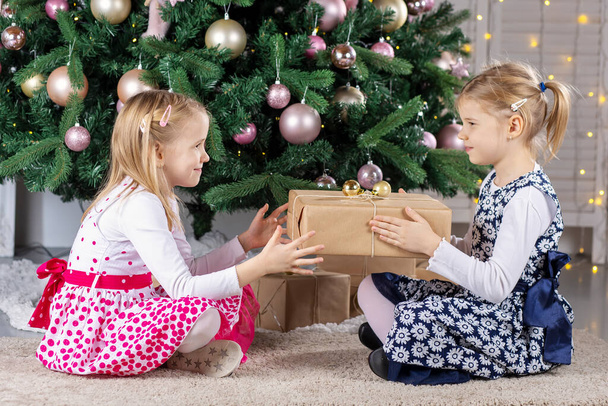Dos lindos niños belleza niña sentados en el árbol chritsmas con cajas de regalo - Foto, imagen