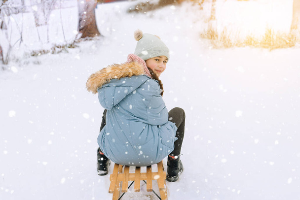 2人の子供が晴れた冬の日に木製のレトロなそりに乗っています。積極的な冬の屋外ゲーム。子供のための冬の活動。公園で雪と遊ぶ子供たち.  - 写真・画像