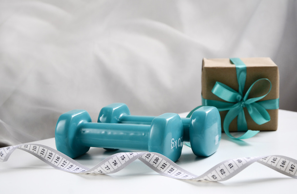 Two sports dumbbells and white measuring tape on white background with copy space, Christmas sport flatlay. Home training, gift. - Foto, immagini