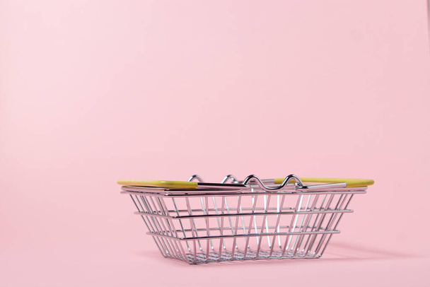 Fém kosár rózsaszín háttérrel. Játékkosár. A szupermarket vásárlási koncepciója. - Fotó, kép