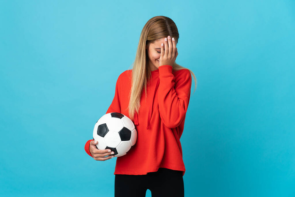 Young football player woman isolated on blue background with tired and sick expression - 写真・画像