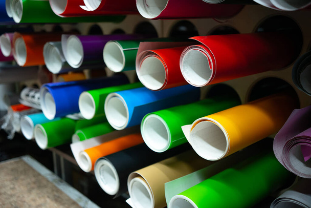 Tubes with multi-colored self-adhesive film on the shelf of the production workshop. - Photo, Image