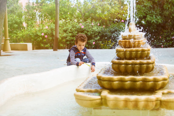 child playing with a leaf in a fountain - Photo, Image
