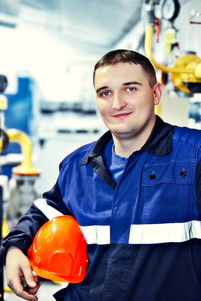 工場の作業環境でヘルメットに若いエンジニアの肖像。ガス労働者は自信を持ってカメラに直接見て - 写真・画像