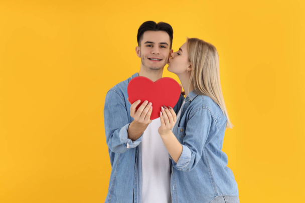 Linda pareja con corazón sobre fondo amarillo - Foto, Imagen