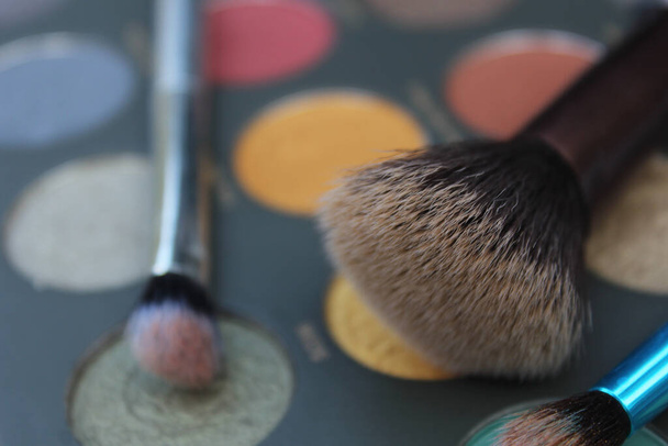 Helder gekleurde cosmetische pigmentpaletten en cosmetische penselen - Foto, afbeelding