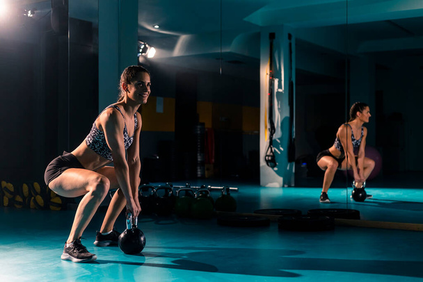 Une jeune femme en forme faisant de l'exercice avec un poids de kettlebell dans la salle de gym. - Photo, image