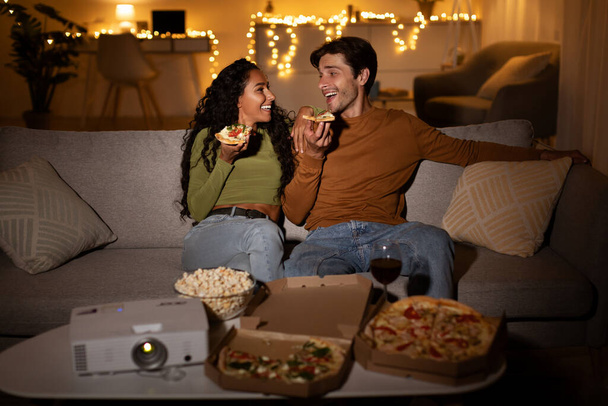 Pärchen isst Pizza Talking Film auf Projektor im Innenraum - Foto, Bild