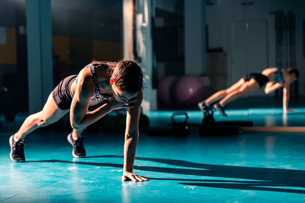 Um exercício feminino jovem no ginásio e fazendo um exercício de torneiras de ombro. - Foto, Imagem