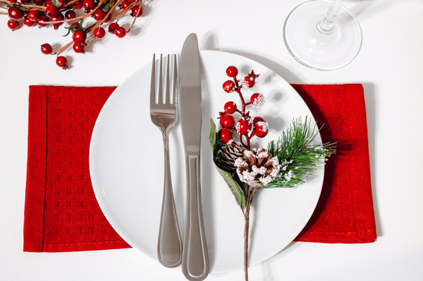 Weihnachtstisch gedeckt. Teller und Besteck auf roter Serviette vorhanden. Dekoration für ein festliches Dinner. - Foto, Bild
