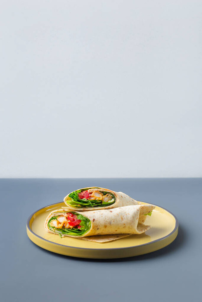 Ζεύγος σάντουιτς με φρέσκο περιτύλιγμα κοτόπουλο και λαχανικά σε κίτρινο χρώμα σε γκρι πιάτο μοντέρνο χρώμα - Φωτογραφία, εικόνα