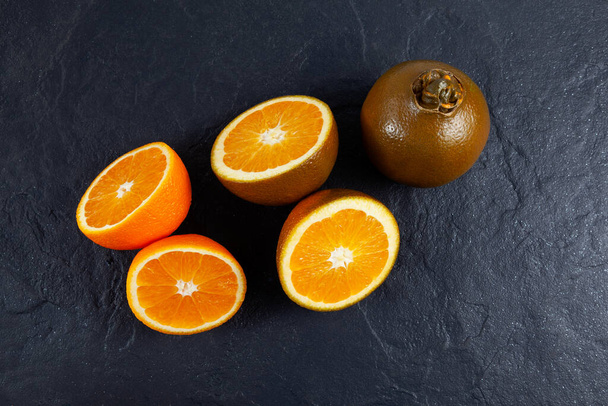 Navel csokoládé narancs, botanikai besorolása Citrus sinensis. Ritka fajta, amely a Rutaceae családhoz tartozik. Narancs sötét kő háttér, felső nézet. - Fotó, kép